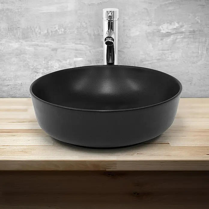 LuxeBath Aufsatzwaschbecken Aufsatzwaschtisch Handwaschbecken Waschplatz Rund - 41,5 x 41,5 cm, Ohne Spezialglasur, Schwarz - Schwarzes Aufsatzwaschbecken mit Chromarmatur auf einer hellen Holzplatte vor einer grauen Wand.