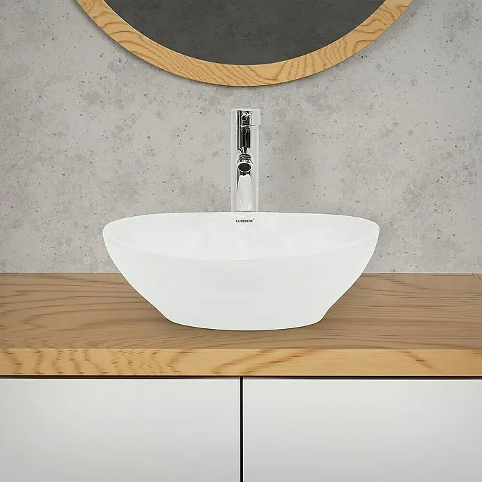 LuxeBath Aufsatzwaschbecken Aufsatzwaschtisch Waschschale Oval Weiß Spülbecken - Ohne Spezialglasur, Weiß - Nahaufnahme eines Waschbeckens mit Armatur und Holzablage vor einer Wand mit Spiegel. Das moderne Design betont die Ästhetik des Badezimmers.