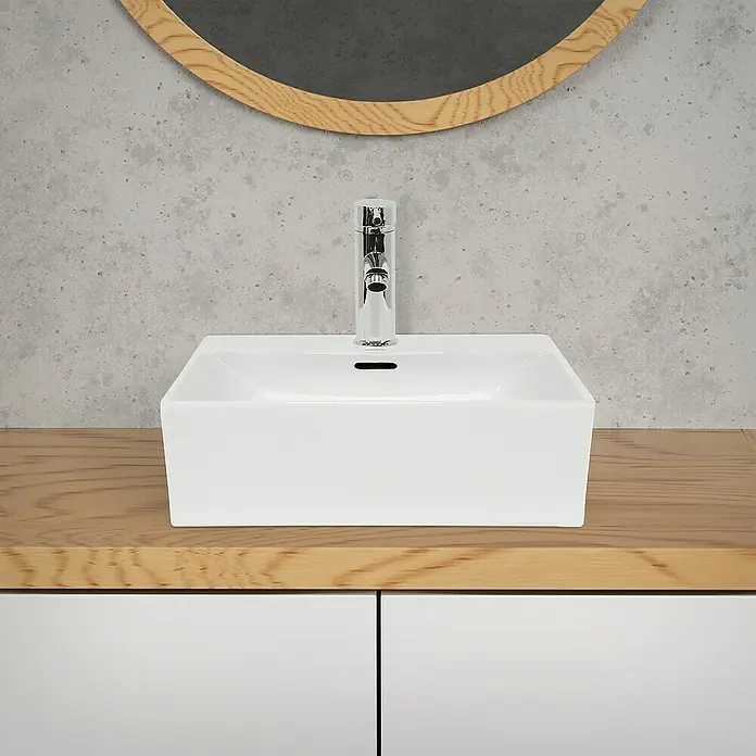 LuxeBath Aufsatzwaschbecken Aufsatzwaschtisch Waschschale Eckig Weiß Spülbecken - Ohne Spezialglasur, Weiß - Nahaufnahme eines modernen weißen Aufsatzwaschbeckens mit Chromarmatur, montiert auf einem Holzunterschrank mit weißen Schubladen und einem runden Spiegel.