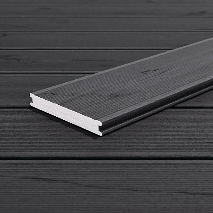Kovalex WPC-Terrassendiele Massiv mit Struktur nach Maß - Räuchereiche, 300 x 14,5 x 2 cm - Nahaufnahme eines einzelnen schwarzen Terrassendielenprofils mit Hohlkammerstruktur, das auf einer Terrasse liegt.