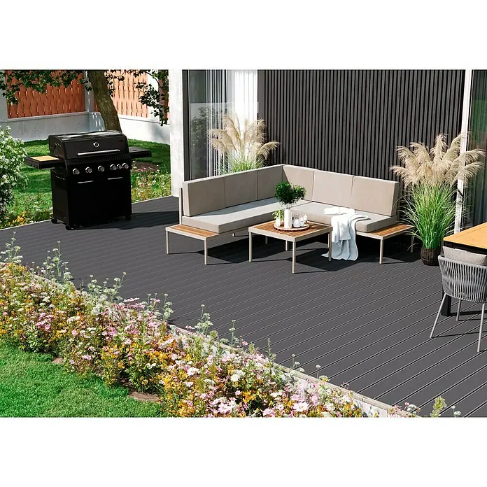 Kovalex WPC-Terrassendiele Massiv mit Struktur nach Maß - Grau, 590 x 14,5 x 2 cm - Eine stilvolle Outdoor-Terrasse mit grauen Dielen, einer grauen Lounge-Ecke und einem schwarzen Gasgrill für entspannte Stunden im Freien.
