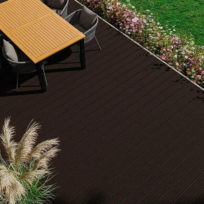 Kovalex WPC-Terrassendiele Exklusiv nach Maß - Schokobraun, Gebürstet, 300 x 14,5 x 2,6 cm - Terrassendielen aus dunklem Verbundmaterial mit einer einladenden Sitzgruppe und üppigem Grün für eine stilvolle Außenanlage.