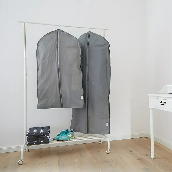 Kleidersack-Set - 2 Stk., Polyester - Zwei graue Kleidersäcke hängen an einer weißen Kleiderstange, darunter Schuhe und eine Box.
