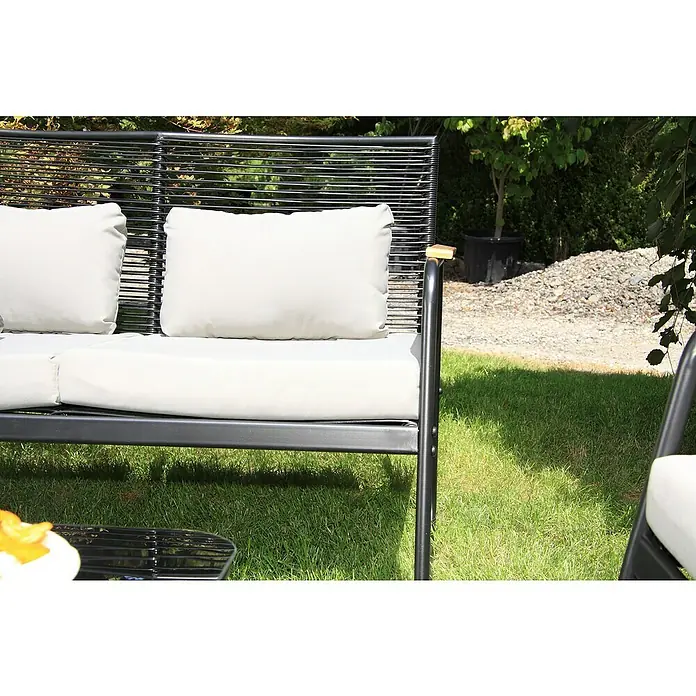 Acamp Loungemöbel-Set Paxos - 4 -tlg., Stahl, Polyrattan, Grau - Nahaufnahme eines modernen Gartensessels mit schwarzen Metallrahmen und hellen Kissen auf einem grünen Rasen.