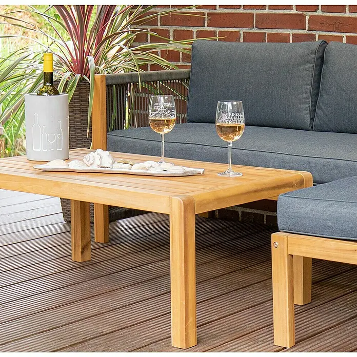 Acamp Loungemöbel-Set Malaga - 3 -tlg., Akazie, Polyester, Braun - Eine Nahaufnahme eines Teakholztisches mit zwei Gläsern Wein, einem Flaschenkühler und Dekor, die eine entspannte Gartenszene zeigen.