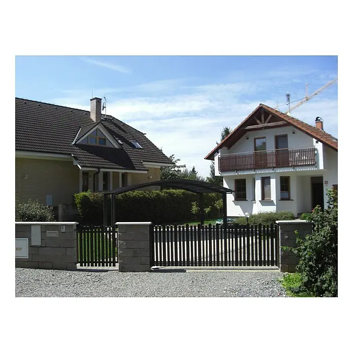 Ximax Carport Portoforte M 80 - Außenmaß inkl. Dachüberstand (B x T): 5,42 x 4,95 m, Doppelcarport, Mattbraun, Schneelast: 100 kg/m² - Blick auf ein modernes Einfamilienhaus mit einem stilvollen Zaun und einem Carport. Der Zaun bietet Privatsphäre und die Überdachung schützt Fahrzeuge.