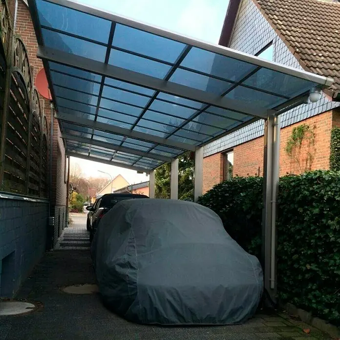 Ximax Carport LINEA Tandem 80 - Außenmaß inkl. Dachüberstand (B x T): 2,73 x 9,83 m, Doppelcarport, Edelstahloptik, Schneelast: 100 kg/m² - Ein Carport mit bläulichem Dach schützt ein abgedecktes Auto. Die Konstruktion bietet Schutz vor Witterungseinflüssen und fügt sich in die Umgebung ein.