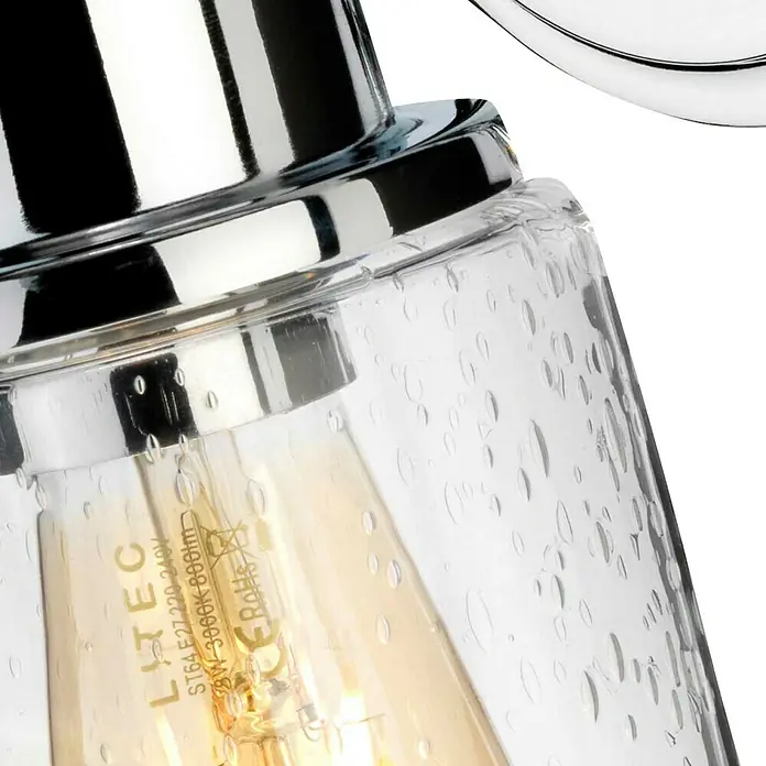 Elstead Wandleuchte Morvah - 60 W, L x B x H: 18,9 x 12 x 30 cm, Chrom, E27 - Nahaufnahme einer stilvollen Lampe mit klarem, strukturiertem Glas und einer sichtbaren Edison-Glühbirne, die warmes Licht ausstrahlt.