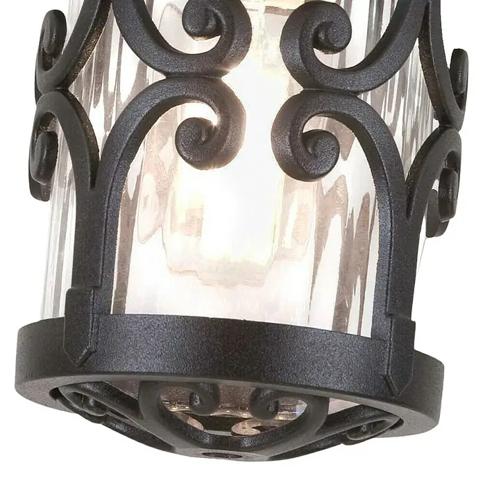 Elstead Außenwandleuchte Hereford - 60 W, 15 x 15 x 26 cm, Schwarz, IP23 - Nahaufnahme einer dekorativen Außenleuchte mit geschwungenem, schwarzem Metallrahmen und strukturierter Glasabdeckung.