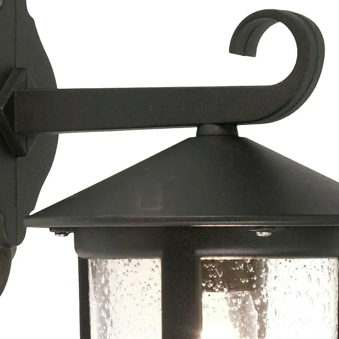 Elstead Außenwandleuchte Hereford - 60 W, 24 x 34,5 x 34,5 cm, Schwarz, IP43 - Nahaufnahme einer schwarzen Außenwandleuchte mit klarem, strukturiertem Glas, die ein warmes Licht ausstrahlt und eine dekorative Note bietet.