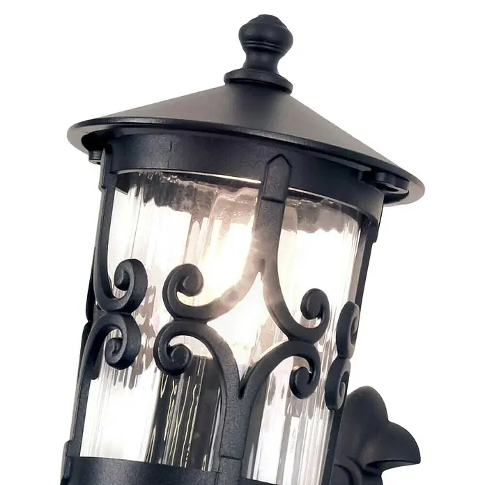 Elstead Außenwandleuchte Hereford - 60 W, 21,5 x 42 x 42 cm, Schwarz, IP23 - Nahaufnahme einer dekorativen schwarzen Außenlaterne mit gewelltem Glas und einer warmen Glühbirne.