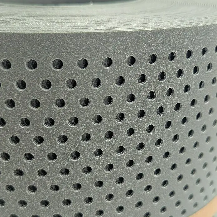 zaun|zu Sichtschutzstreifen Polyal Eco Gelocht 20% - 26 m x 19 cm x 0,1 cm, Salbei - Nahaufnahme einer perforierten grauen Materialrolle, die eine gleichmäßige Anordnung von runden Löchern aufweist.