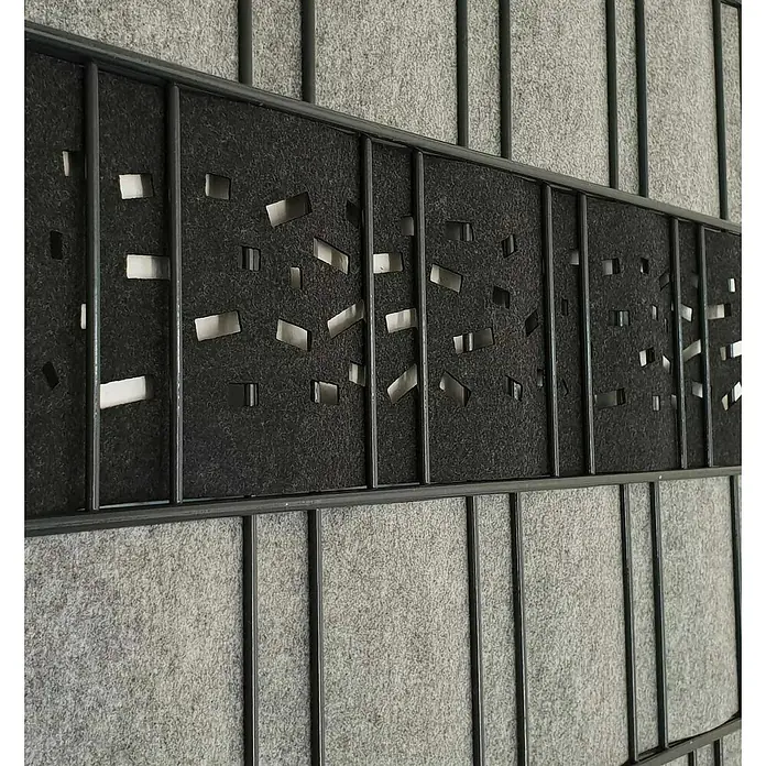 zaun|zu Sichtschutzstreifen Dekor Criss-Cross - 2,6 m x 19 cm x 0,2 cm, Schwarzgrau - Nahaufnahme einer Raumteilerwand mit einem Design aus grauen Paneelen, die durchbrochene schwarze Akzente und ein schlankes Metallgitter aufweisen.