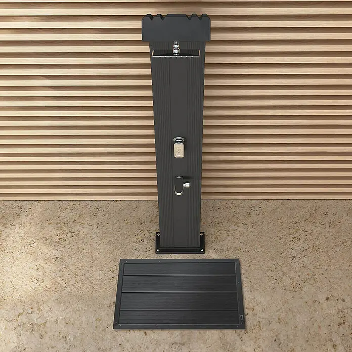 Home Deluxe Terrassenfliese GAIA - 105 cm x 63 cm x 55 mm, Anthrazit, Matt - Eine moderne Außendusche mit Duschmatte vor einem Hintergrund aus Holzpaneelen. Das schlanke Design fügt sich nahtlos in jeden Garten ein.