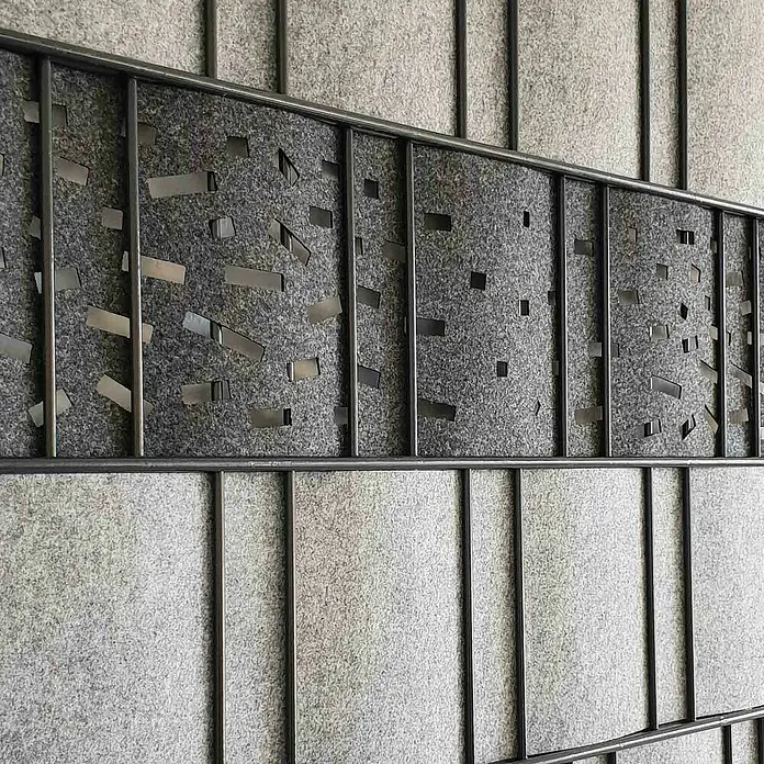 zaun|zu Sichtschutzstreifen Dekor Criss-Cross - 2,6 m x 19 cm x 0,2 cm, Anthrazit - Detailaufnahme einer Raumteiler-Wand mit Textur und Metallakzenten. Das Design kombiniert Stoffelemente mit einer modernen Metallstruktur.