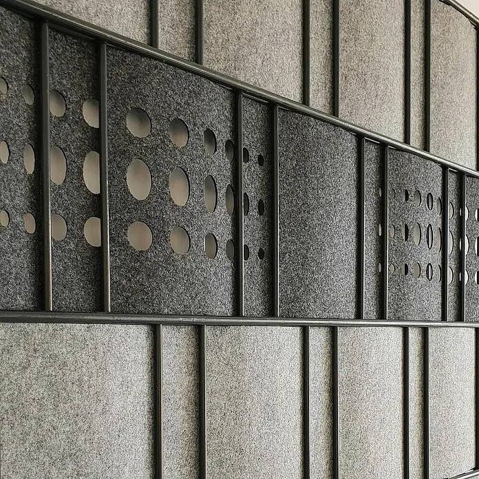 zaun|zu Sichtschutzstreifen Dekor Bubble - 2,6 m x 19 cm x 0,1 cm, Anthrazit - Detailaufnahme einer grau melierten Akustikwand mit Lochmuster und Metallrahmen. Schallabsorption für Büro und Wohnraum.