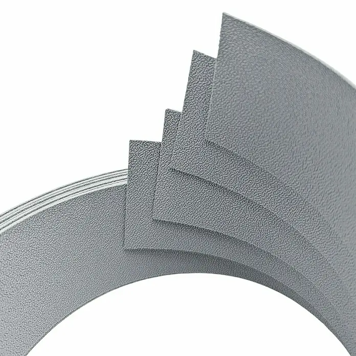 zaun|zu Sichtschutzstreifen Premium 1/4 Set - 2,55 m x 4,7 cm x 0,1 cm, Fenstergrau - Graue Kunststoffplatten mit körniger Textur, die in einer gebogenen Form gestapelt sind. Das Material wirkt robust und widerstandsfähig.