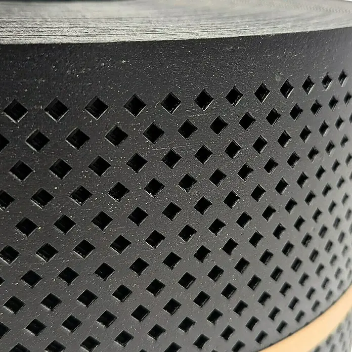 zaun|zu Sichtschutzstreifen Polyal Eco Gelocht Diamant - 50 m x 19 cm x 0,1 cm, Schwarz - Nahaufnahme eines schwarzen perforierten Bandes, das aufgerollt ist und ein regelmäßiges Muster aus quadratischen Löchern aufweist.