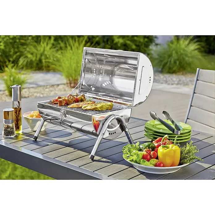 Grillstar Holzkohlegrill Dallas - Grillfläche (B x T): 34 x 22 cm, Silber - Tragbarer Grill auf einem Tisch im Freien mit Gemüse, Gewürzen und grünem Geschirr. Ideal für Picknicks und Camping.