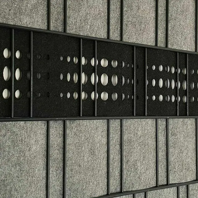 zaun|zu Sichtschutzstreifen Dekor Bubble - 2,6 m x 19 cm x 0,1 cm, Schwarzgrau - Detailaufnahme einer modernen Raumteiler-Wand mit grauem Filz und einem horizontalen Band aus schwarzem Filz mit kreisförmigen Aussparungen.