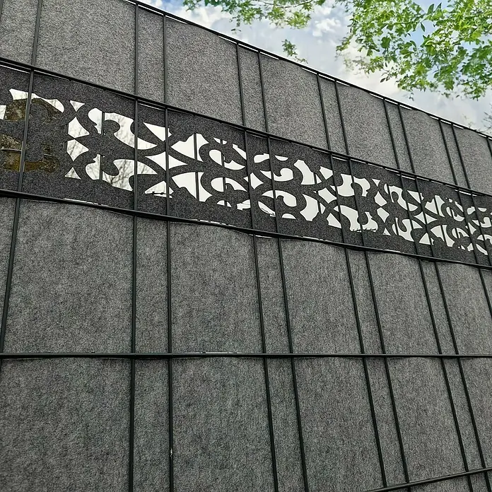 zaun|zu Sichtschutzstreifen Design Orient - 2,6 m x 19 cm x 0,2 cm, Schwarzgrau - Nahaufnahme eines grauen Sichtschutzzauns mit einem dekorativen Ausschnitt, der Privatsphäre bietet und gleichzeitig Licht durchlässt.