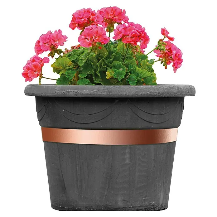 Bellissa Kupferband - Kupfer, Selbstklebend - Nahaufnahme eines grauen Pflanzgefäßes mit einem Kupferband in der Mitte, bepflanzt mit rosafarbenen Geranienblüten und grünen Blättern.