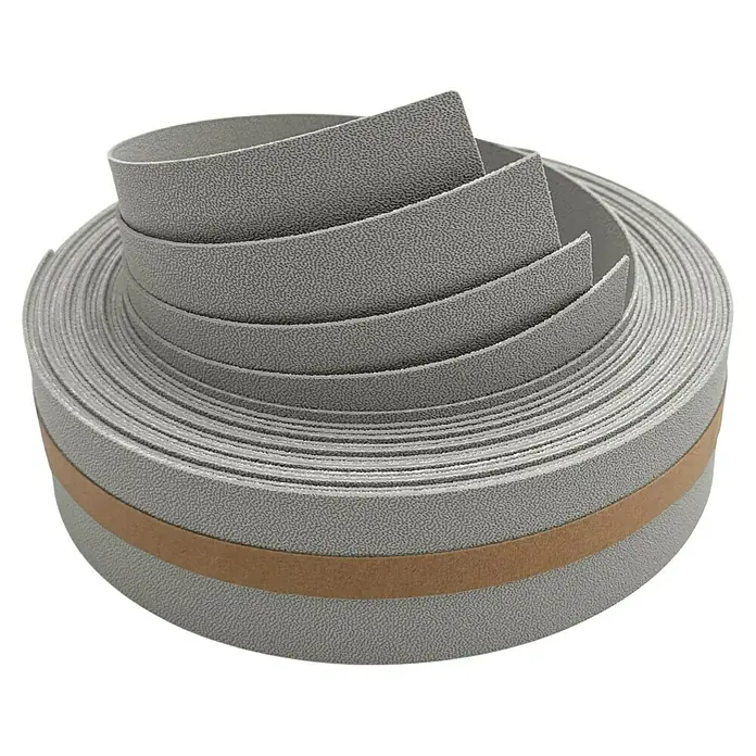 zaun|zu Sichtschutzstreifen Premium 1/4 Set - 2,55 m x 4,7 cm x 0,1 cm, Steingrau - Nahaufnahme einer Rolle grauen, strukturierten Kantenumleimers mit braunem Klebestreifen, ideal für Möbelprojekte und DIY-Anwendungen.