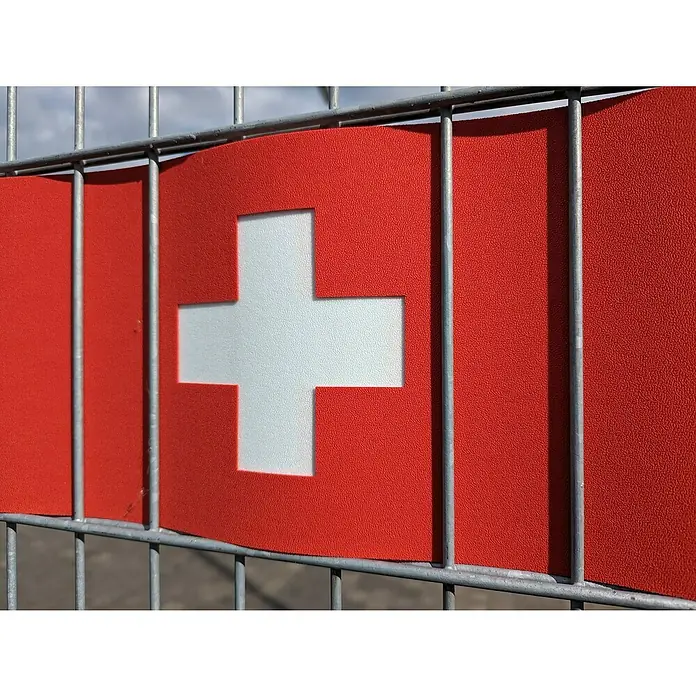 zaun|zu Sichtschutzstreifen Schweiz - L x B x H: 2,55 m x 19 cm x 0,3 cm, Rot, Schweiz, 3 Für 2 - Nahaufnahme einer Schweizer Flagge, die an einem Metallzaun befestigt ist. Das rote Banner zeigt ein markantes weißes Kreuz.