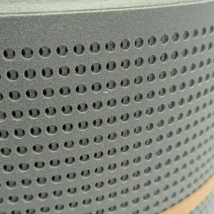 zaun|zu Sichtschutzstreifen Polyal Eco Gelocht 30 % - 26 m x 19 cm x 0,1 cm, Salbei - Nahaufnahme eines Luftreinigers mit einem perforierten Metallgehäuse, das eine effektive Filterung der Luft gewährleistet.