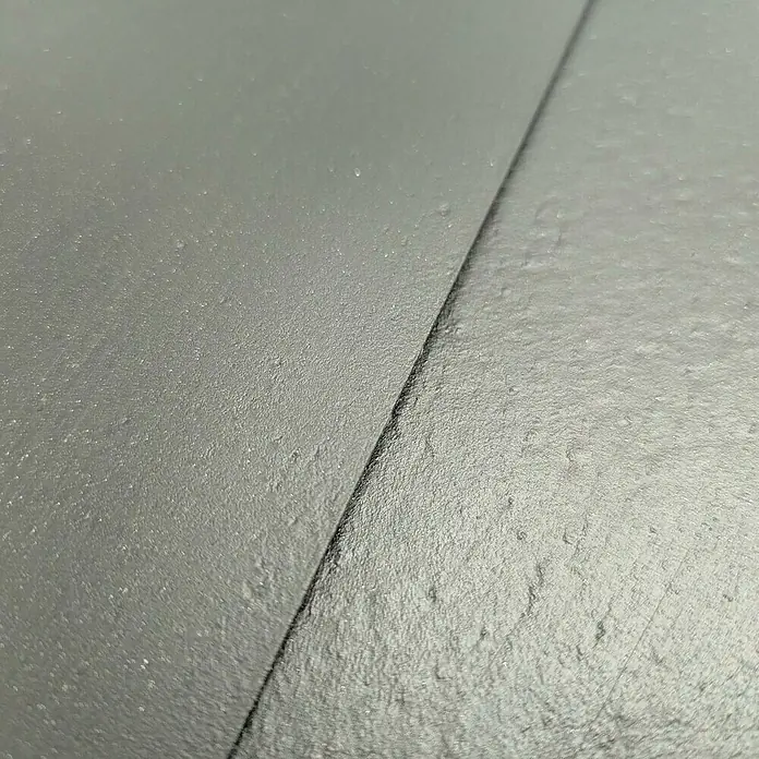 zaun|zu Sichtschutzstreifen Eco Salbei - 50 m x 19 cm x 0,1 cm, Salbei, 1 Stk. - Nahaufnahme von zwei grauen Steinfliesen, die sich treffen und eine interessante Textur und ein Muster erzeugen.