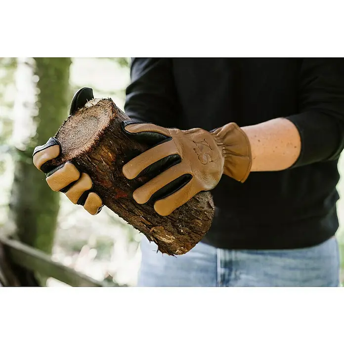 Kent & Stowe Gartenhandschuhe Sure & Soft - S, Braun/Schwarz - Nahaufnahme von Handschuhen beim Halten eines Holzscheits. Ideal für Gartenarbeiten, Holzarbeiten und andere Outdoor-Aktivitäten.