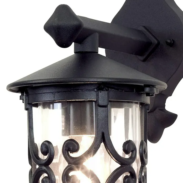 Elstead Außenwandleuchte Hereford - 60 W, 21 x 31 x 31 cm, Schwarz, IP23 - Nahaufnahme einer schwarzen Außenwandleuchte mit klarem Glas und dekorativen Verzierungen, die eine warme Atmosphäre erzeugt.