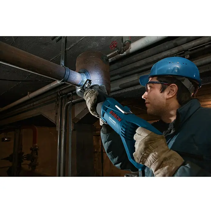 Bosch Professional Säbelsäge GSA 1100 E - 1.100 W, Hublänge: 28 mm - Mann, der eine blaue Bosch GSA 1100 E Säbelsäge zum Schneiden eines Rohrs in einem Keller verwendet.\n
