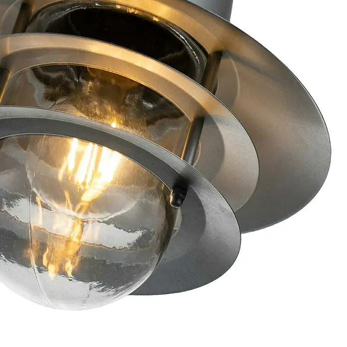 Elstead Pendelleuchte Copenhagen - 60 W, L x B x H: 22 x 22 x 37,5 cm, Silber, E27 - Nahaufnahme einer Außenleuchte mit Metallgehäuse und einer klaren Glühbirne, die ein warmes Licht ausstrahlt.