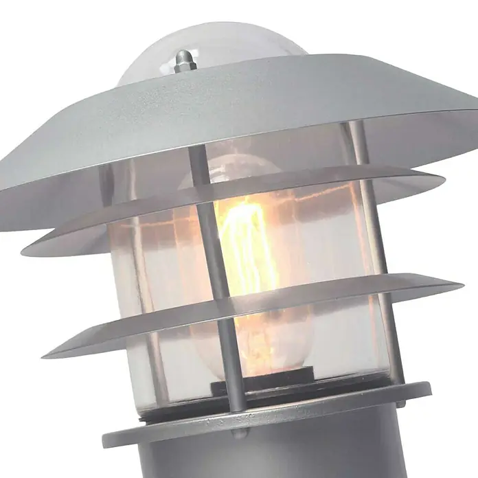 Elstead Außenwandleuchte Helsingor - 60 W, 21,8 x 30,5 x 30,5 cm, Silber, IP44 - Nahaufnahme einer modernen Außenleuchte mit silbernem Gehäuse und warmweißem Licht, das durch klares Glas scheint.