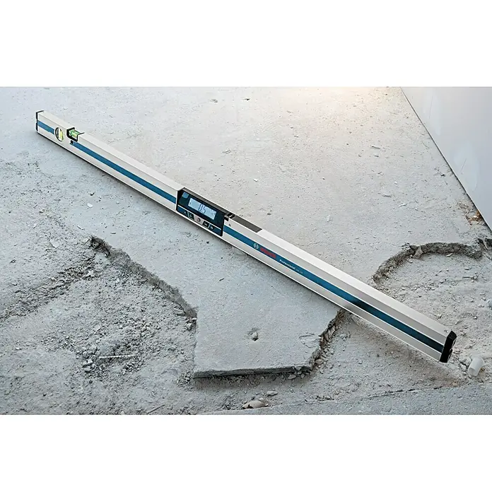 Bosch Professional Digitale Wasserwaage GIM 120 - 1.250 mm, Messbereich: 0 ° - 360 ° (4 x 90 °) - Ein Bosch Professional Wasserwaage mit digitaler Anzeige liegt auf einem unebenen Betonboden. Das Werkzeug ist ideal für präzise Messungen.