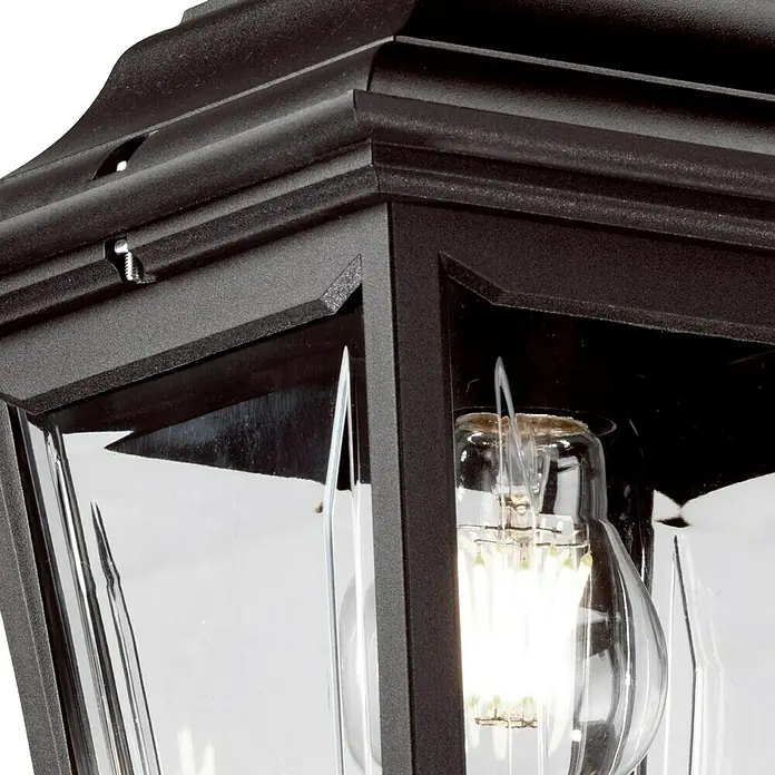 Elstead Pendelleuchte Kerry - 60 W, Farbe Gehäuse: Schwarz, 20,4 x 20,5 x 62,5 cm, Ohne Leuchtmittel - Nahaufnahme einer Außenleuchte mit klarem Glas und einer Glühbirne, die ein warmes, einladendes Licht ausstrahlt. Die Leuchte ist in dunklem Farbton gehalten.