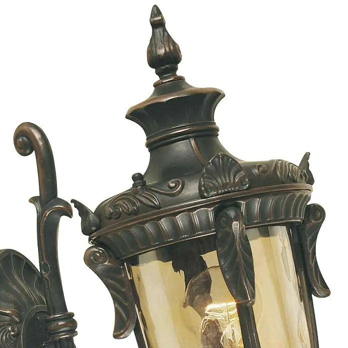Elstead Außenwandleuchte Philadelphia - 60 W, 24 x 43 x 43 cm, Old Bronze, IP44, Up - Nahaufnahme einer dekorativen Wandleuchte mit bronzefarbenem Finish und bernsteinfarbenem Glas, die ein warmes Licht ausstrahlt.