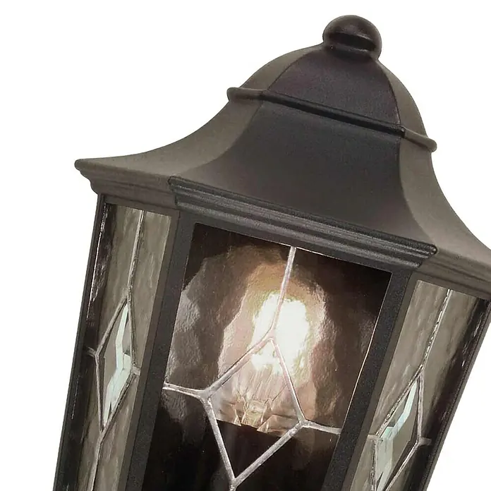 Elstead Außenwandleuchte Norfolk - 60 W, 12,5 x 35,9 x 39,5 cm, Schwarz, IP44 - Nahaufnahme einer schwarzen Außenlaterne mit verzierter Glasscheibe und einer warm leuchtenden Glühbirne, die eine gemütliche Atmosphäre erzeugt.
