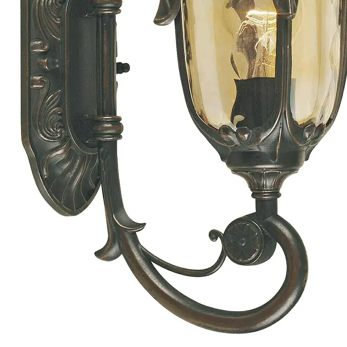 Elstead Außenwandleuchte Philadelphia - 60 W, 24 x 43 x 43 cm, Old Bronze, IP44, Up - Eine Wandleuchte mit einem geschwungenen Arm und einem bernsteinfarbenen Glasschirm, die ein warmes Licht ausstrahlt.