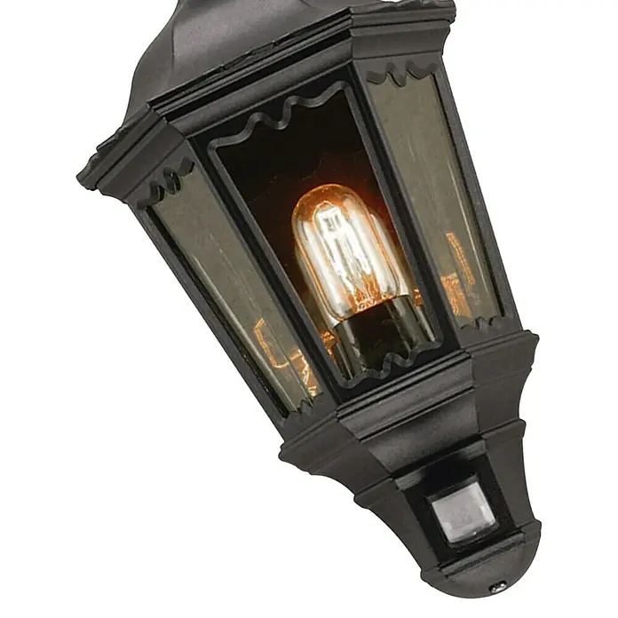 Elstead Außenwandleuchte Medstead - 60 W, 14 x 49,5 x 49,5 cm, Schwarz, IP44, Mit Bewegungsmelder - Nahaufnahme einer stilvollen schwarzen Außenlaterne mit warmem Licht, die eine gemütliche Atmosphäre erzeugt.