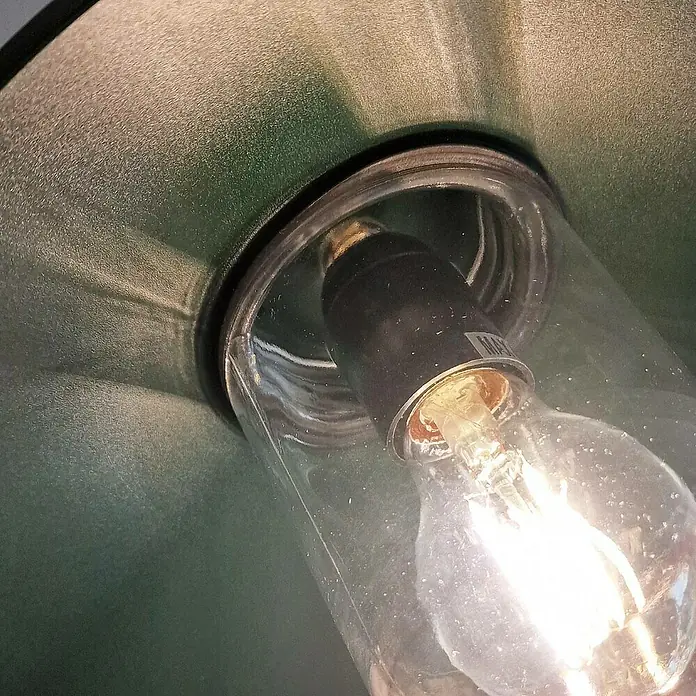 Elstead Außenwandleuchte Klampenborg - 60 W, 31,8 x 31,8 x 31,8 cm, Fir Green, IP44 - Nahaufnahme einer Edison-Glühbirne in einer grünen Lampe, die warmes Licht ausstrahlt und eine gemütliche Atmosphäre schafft.