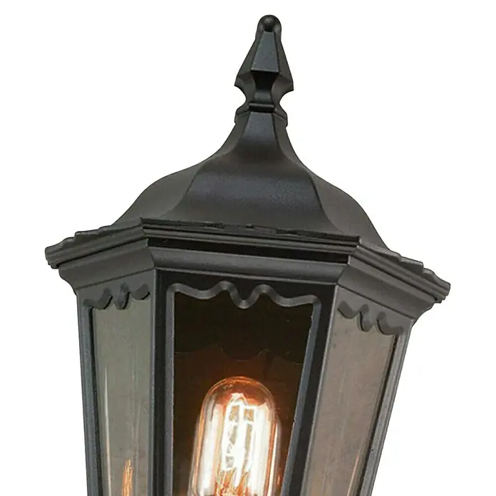 Elstead Außenwandleuchte Medstead - 60 W, 14 x 44,5 x 44,5 cm, Schwarz, IP44, Ohne Bewegungsmelder - Nahaufnahme einer schwarzen Außenlaterne mit dekorativer Spitze und warmem Glühbirnenlicht, die eine stimmungsvolle Atmosphäre schafft.