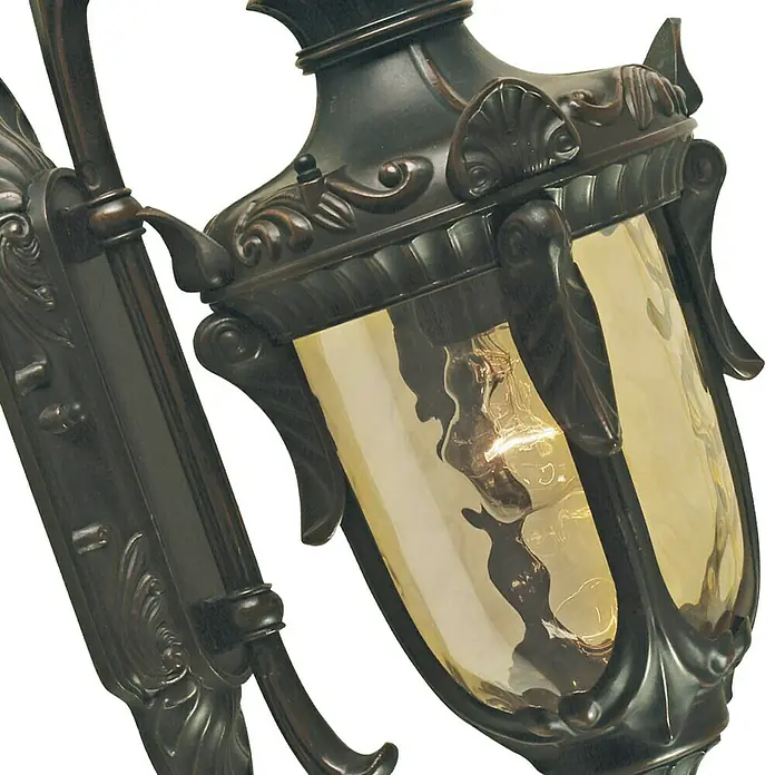 Elstead Außenwandleuchte Philadelphia - 60 W, 24 x 43 x 43 cm, Old Bronze, IP44, Down - Nahaufnahme einer Wandleuchte im Vintage-Stil mit verzierter Bronzehalterung und bernsteinfarbenem Glasschirm, der eine Glühbirne zeigt.
