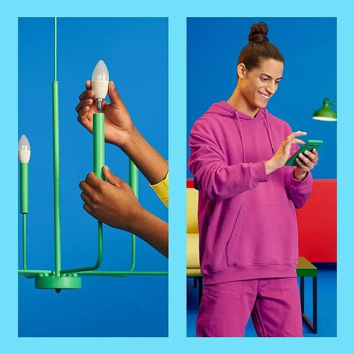 Philips Wiz Smart-LED-Lampe - E14, Dimmbarkeit: Dimmbar, RGBW, 470 lm, 4,6 W - Smarte LED-Lampe wird in eine grüne Lampe eingesetzt. Ein Mann mit einem Smartphone im farbenfrohen Raum.