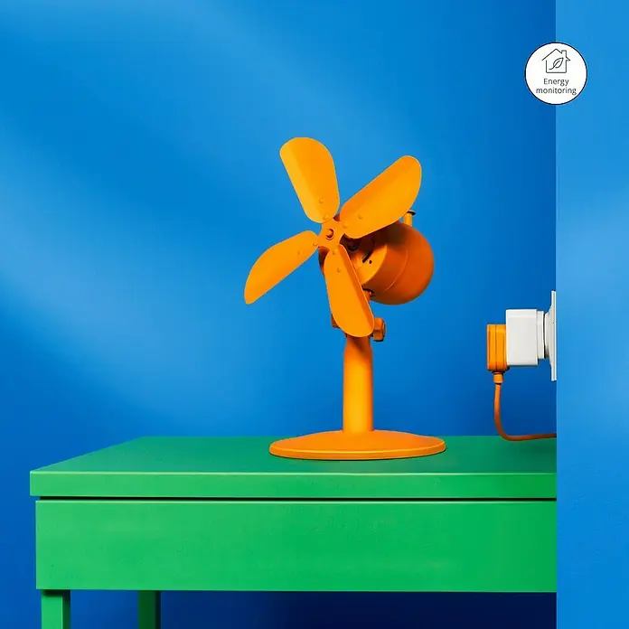 Philips Wiz Smart-Steckdose - Innen, IP20, Weiß, 1 Stk. - Oranger Ventilator, an grüne Oberfläche angeschlossen, vor blauem Hintergrund, mit Energiekontrollanzeige.