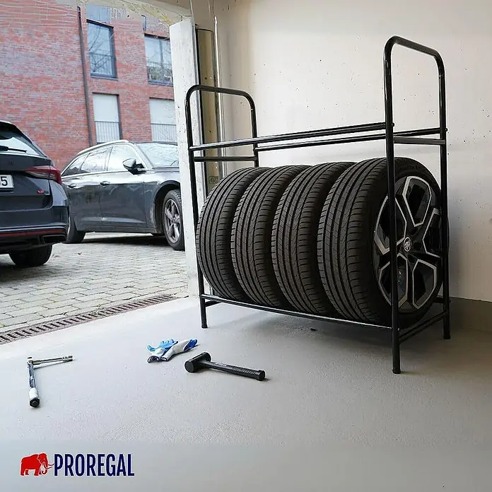 Proregal Reifenregal CARRERO - Schrauben, Schwarz - Bild eines schwarzen Proregal-Reifenregals mit vier Reifen in einer Garage, Werkzeuge liegen daneben.
