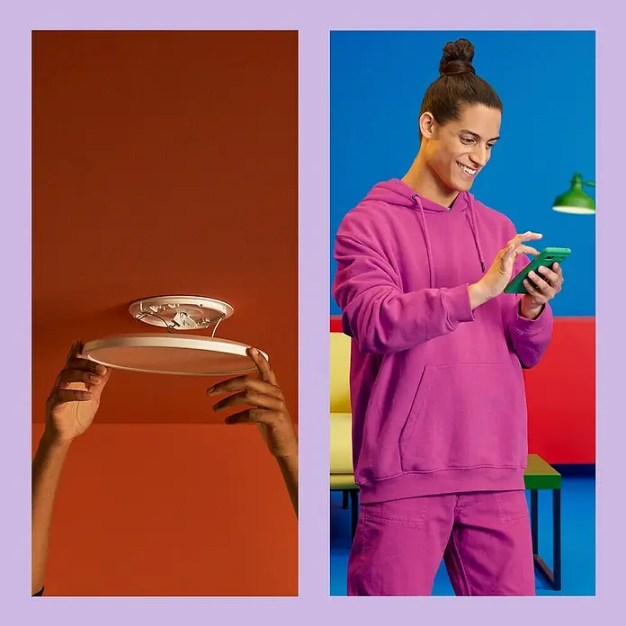 Philips Wiz LED-Deckenleuchte rund Tunable White SuperSlim - 14 W, Ø x H: 24,2 x 2,3 cm, Farbe Gehäuse: Weiß, Kaltweiß - Deckenleuchte wird montiert, während ein Mann daneben auf sein Handy schaut. Die moderne Leuchte sorgt für helles, effizientes Licht im Raum.