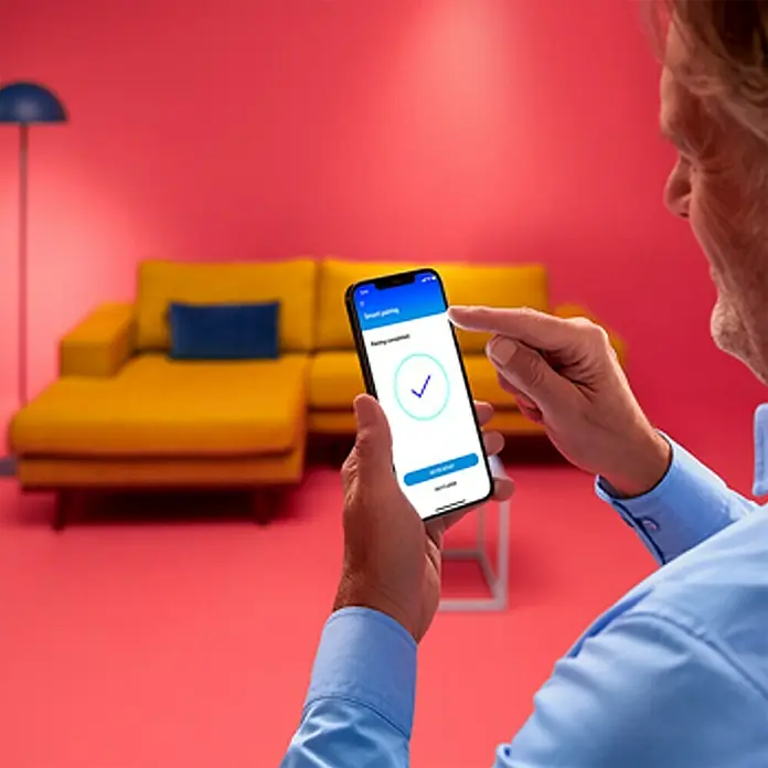 Philips Wiz LED-Panel Tunable White Slim Design - 36 W, L x B x H: 119,5 x 29,5 x 4 cm, Weiß, Kaltweiß - Nahaufnahme einer Person, die ein Smartphone mit einer App bedient, die ein grünes Häkchen zeigt. Intelligente Technologie im Alltag.