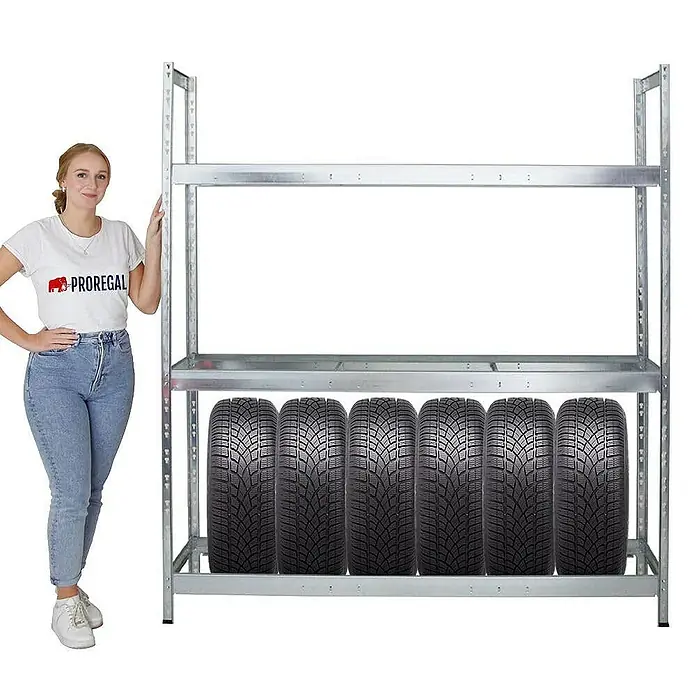 Proregal Reifenregal Mega Deal Tiger XL - Stecken, Verzinkt - Ein Metallregal mit Reifen in der unteren Ebene, daneben steht eine Frau zur Größenveranschaulichung. Optimal für die Reifenlagerung.